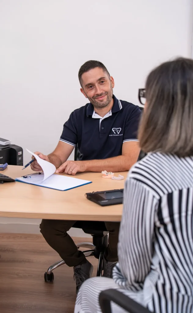 Il dentista illustra il preventivo scritto a una paziente alla scrivania