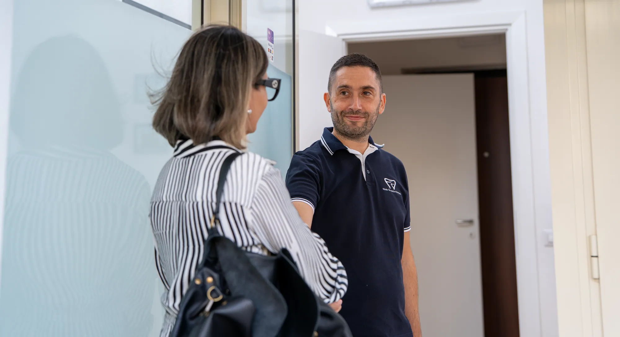 Il dentista accoglie una paziente all'ingresso dello studio